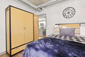 a bedroom with a blue blanket and a wood cabinet