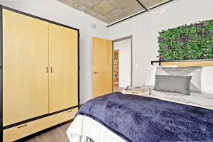 a bedroom with a blue blanket and a wooden cabinet