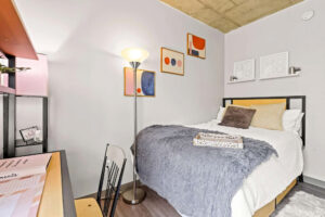 a bed with a grey blanket and a lamp