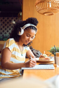 a woman wearing headphones writing in a notebook