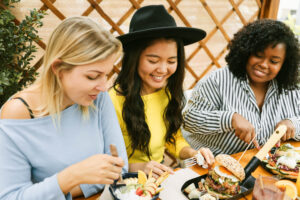 a group of women sitting at a table eating food